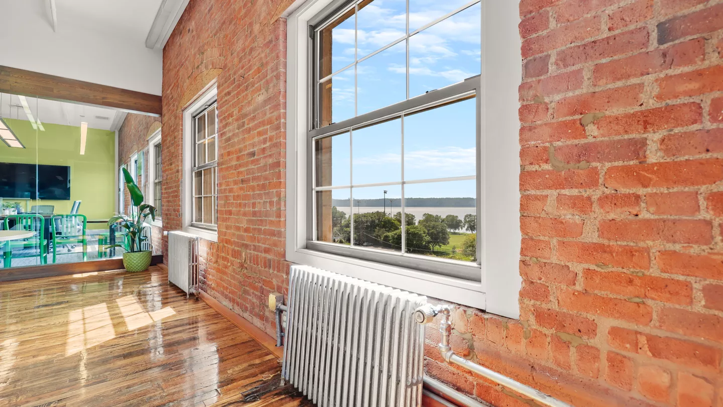 The exterior of The Cosmopolitan building, with a few cars parked in the parking lot. The sky is blue, scattered with a few white clouds, creating a bright and clear day.