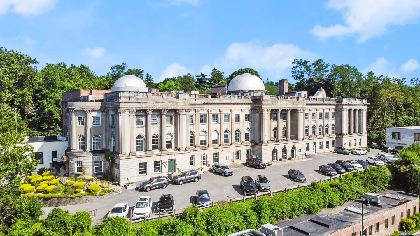 An aerial view of Irvington, showing The Cosmopolitan building from the back. The Irvington train station and the Hudson River are visible, highlighting the surrounding area's layout and natural beauty.